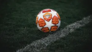 Spalvingas futbolo kamuolys guli ant nupjautos žalios futbolo aikštės žolės.