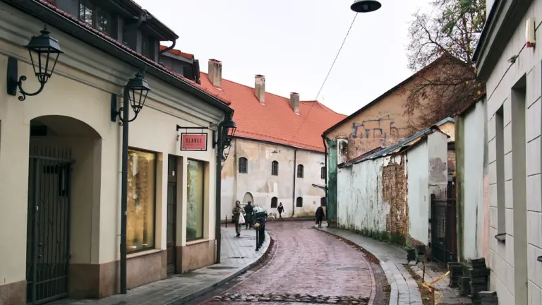 Sena akmenimis grįsta gatvė su istoriniais pastatais senamiestyje, primenanti prekybos ištakas.