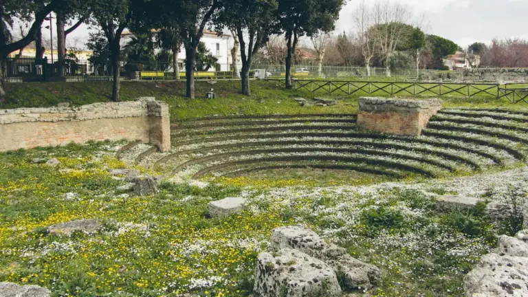 Senovinio amfiteatro griuvėsiai žaliuojančiame lauke su paveldo apsaugos atmosfera.