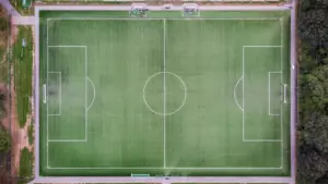 Tuščias futbolo aikštės vaizdas iš viršaus, paruoštas svarbioms futbolo rungtynėms.