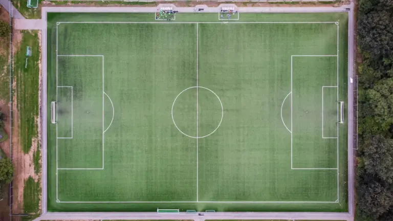 Tuščias futbolo aikštės vaizdas iš viršaus, paruoštas svarbioms futbolo rungtynėms.