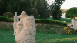 Dvi abstrakčios akmens skulptūros žaliuojančiame Pakruojo kraštovaizdyje vasaros metu