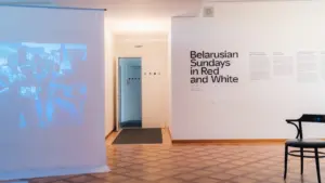Minimalistinė parodos erdvė su informaciniu stendu ir kėde Panevėžyje