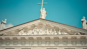 Iškilus Kauno arkikatedros bazilikos frontonas su šventųjų statulomis ir kryžiumi.