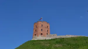 Gedimino pilies bokštas ant žalios kalvos saulėtą vasaros dieną Vilniuje.