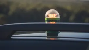 Ryškus įspėjamasis švyturėlis ant automobilio stogo, simbolizuojantis budrumą ir pasirengimą ekstremalioms situacijoms.