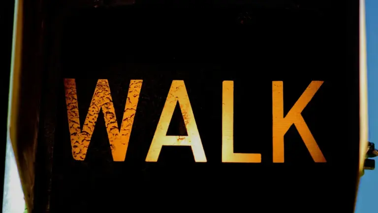 Švieslentė su užrašu WALK, raginanti pėsčiuosius judėti ir būti aktyviems.