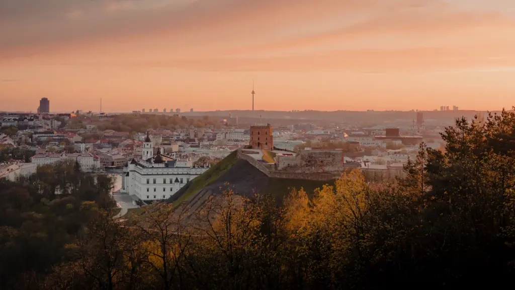 Vaizdas į Vilnių ir Gedimino pilies bokštą šiltų spalvų saulėlydžio šviesoje.