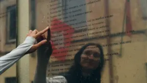 Moteris rodo į žmogaus teises atspindintį stendą Vilniaus senamiesčio gatvėje spalio dieną.
